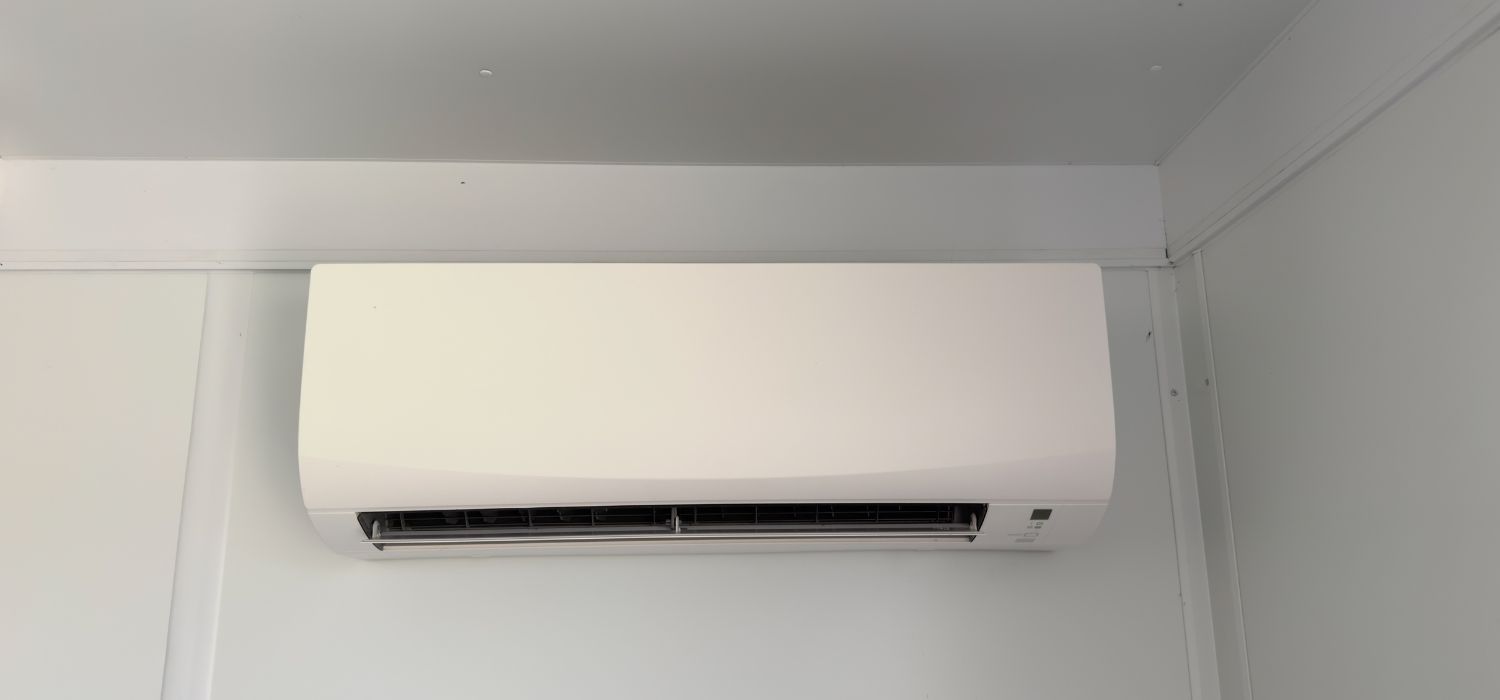 Wall-mounted mini split air conditioning unit installed near the ceiling inside a modern residential room.